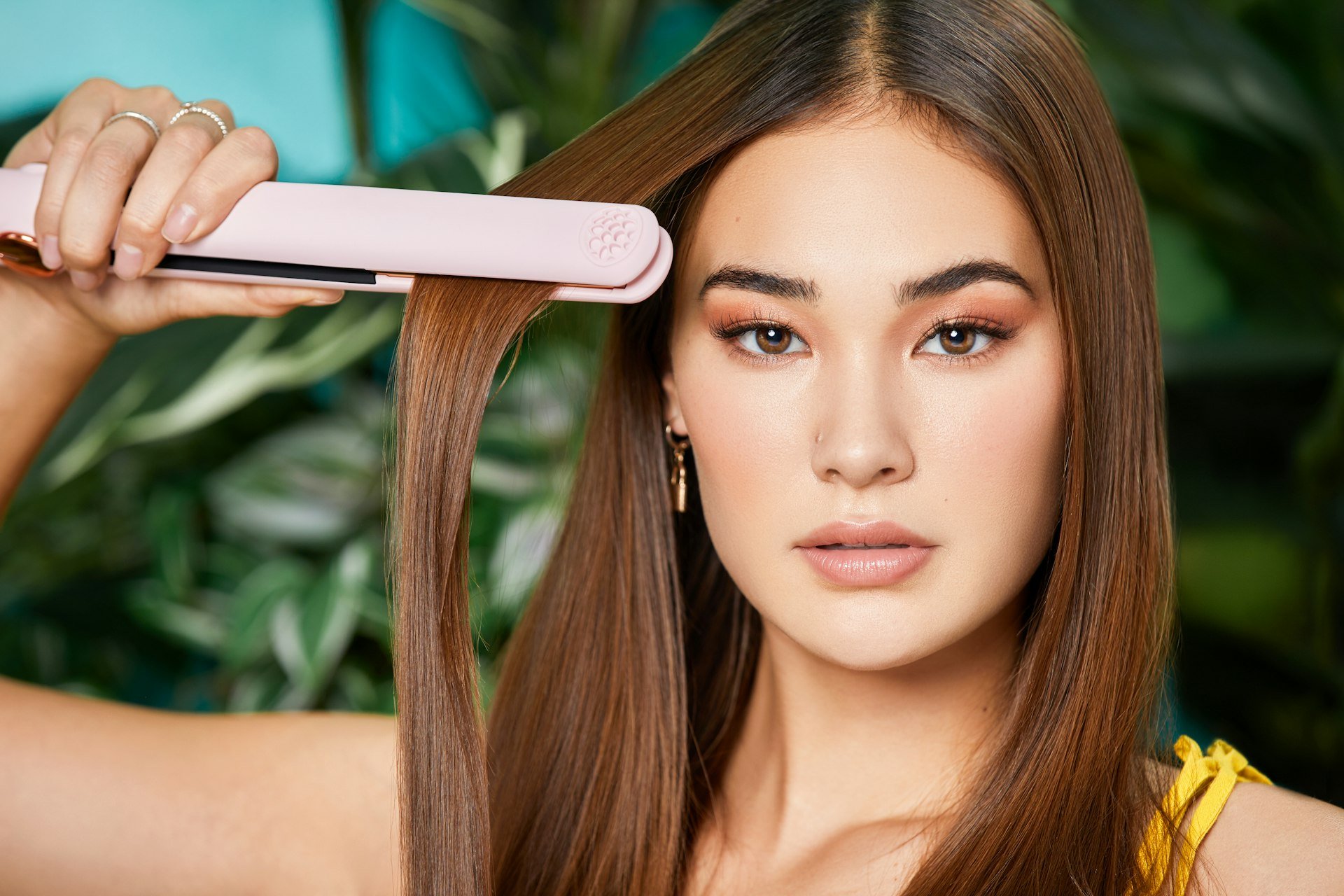 Straightening coloured hair with a flat iron, adding thermal stress that dulls the pigment