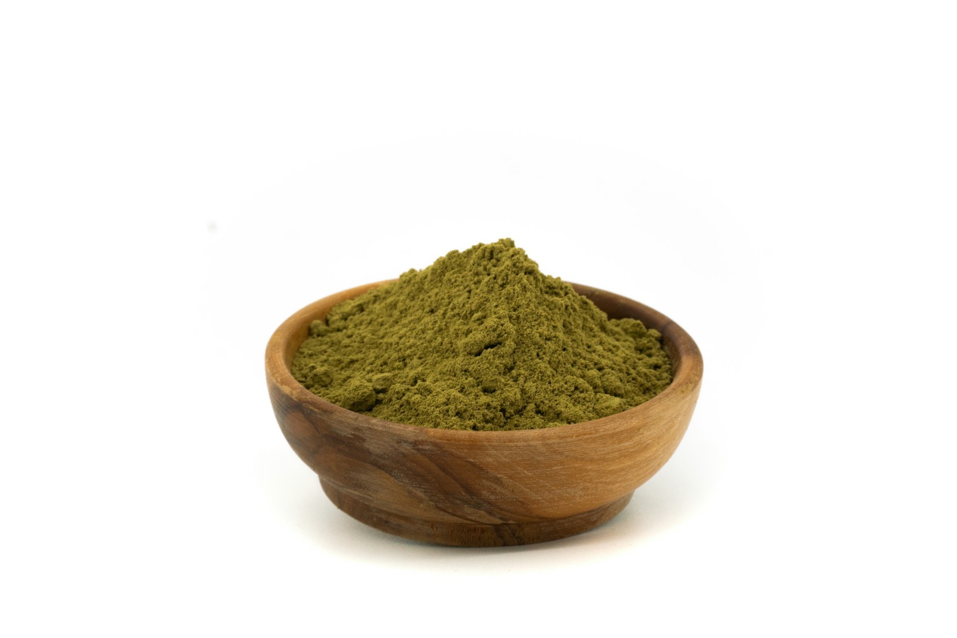 Green henna powder in a wooden bowl, the plant dye that stains hair and stays put through later colouring